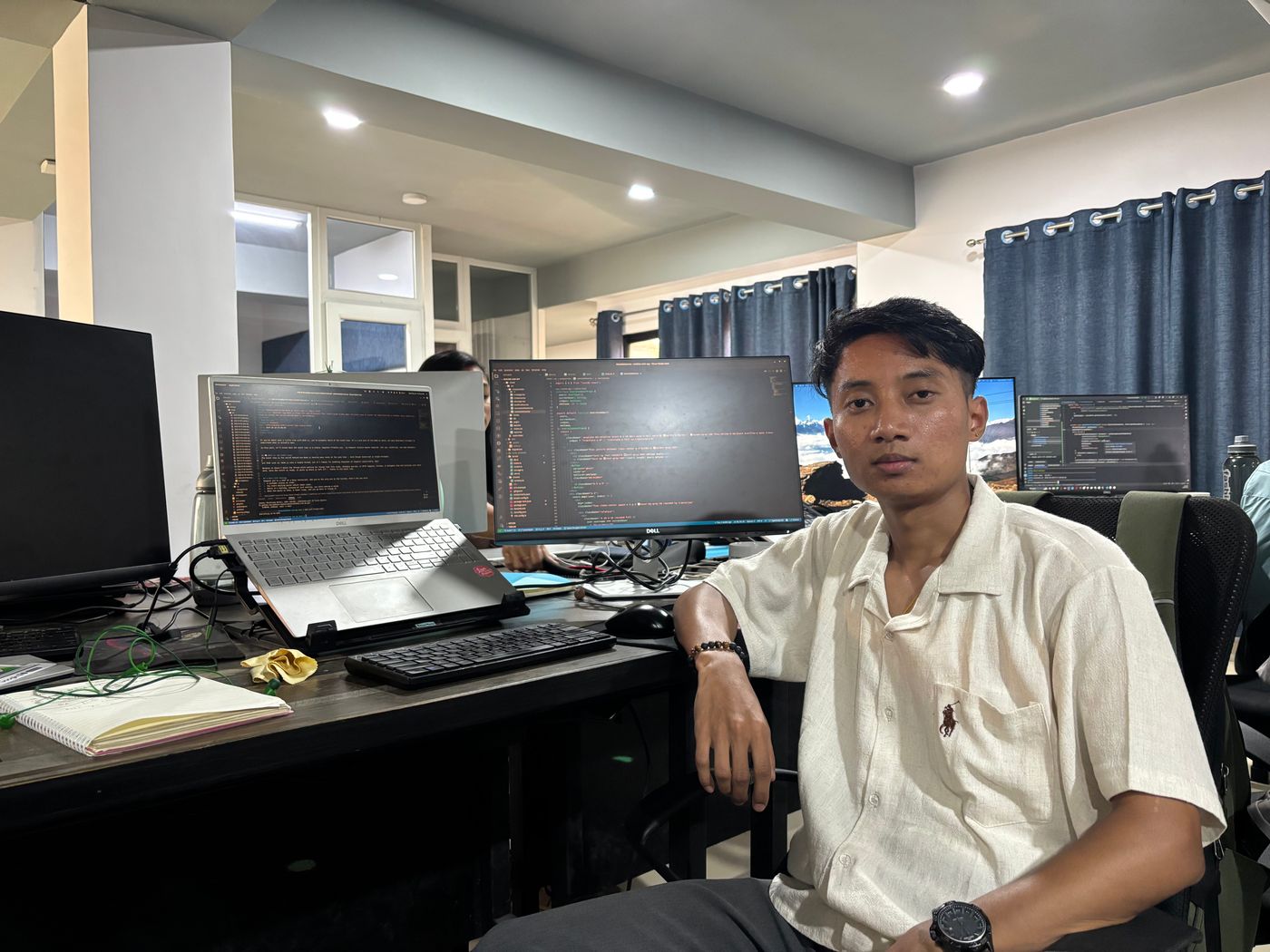 Aashish sitting in front of her desk, smiling